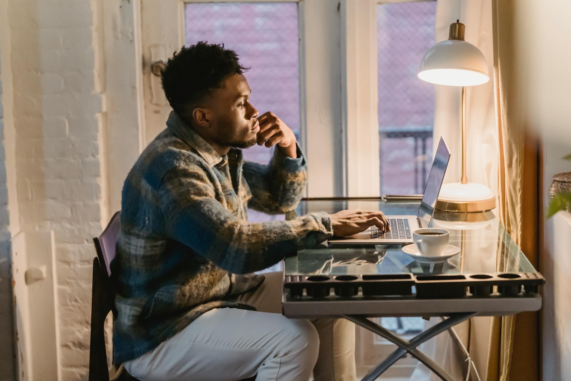 Man contemplating while looking out a window, with a thoughtful expression, possibly reflecting on social media strategy and Instagram authenticity.