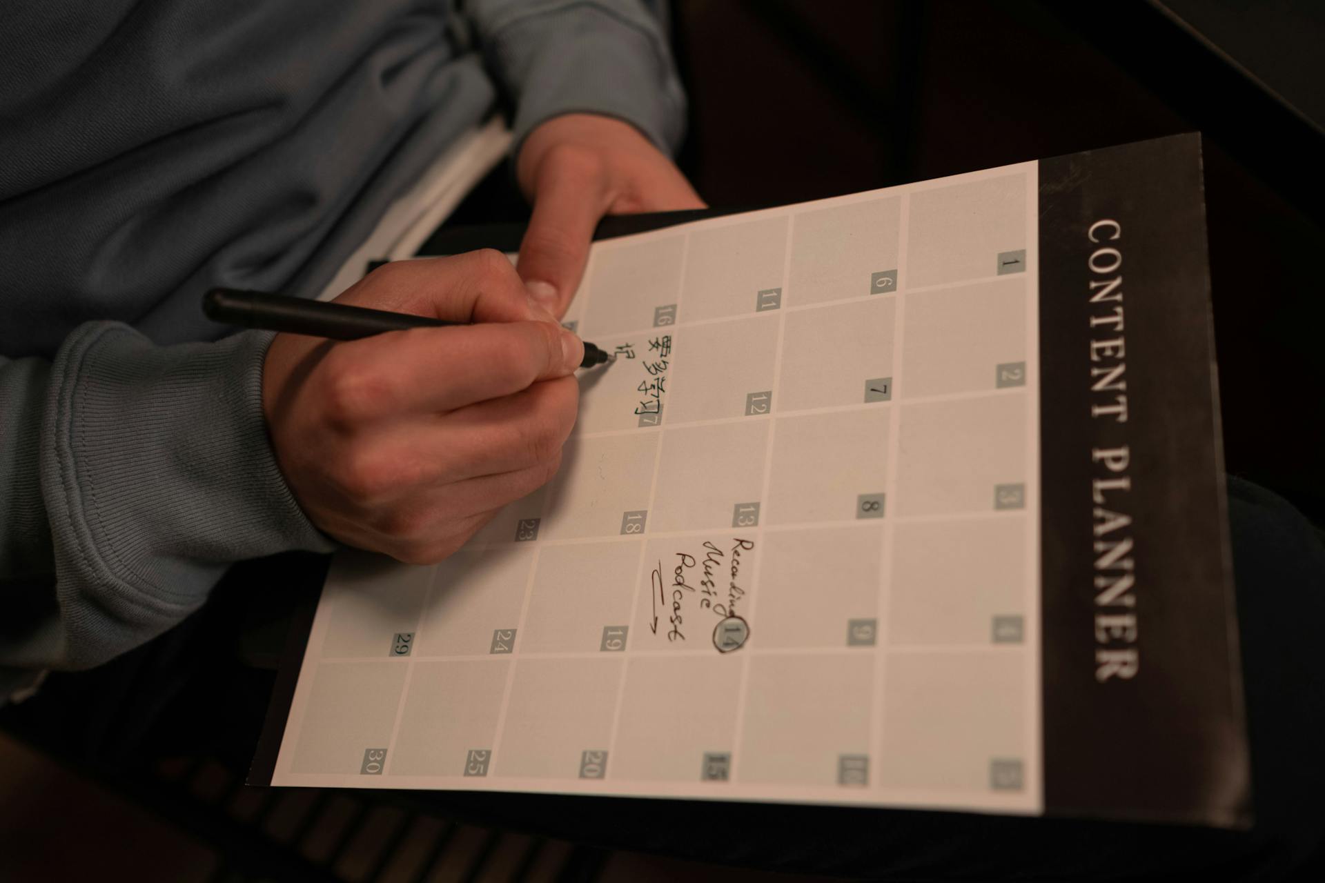 Close-up of hands holding a pen and writing on a 'Content Planner' schedule, emphasizing strategic planning for social media consistency.