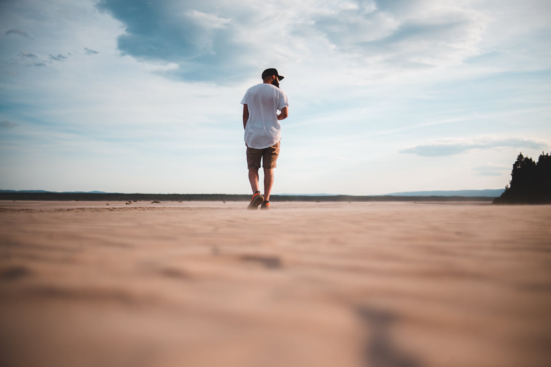 Entrepreneur embarking on a journey across a vast sandy terrain under a clear blue sky, symbolizing 'Purposeful Resilience in Entrepreneurship'