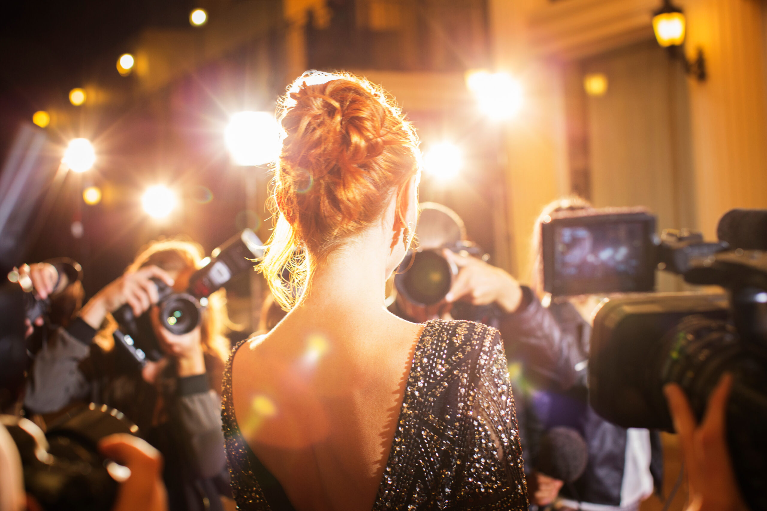 Female celebrity facing a crowd of reporters and fans at a red carpet event, with flash photography capturing the moment, illustrating the concept of Viral Marketing Strategies through public attention and media presence.