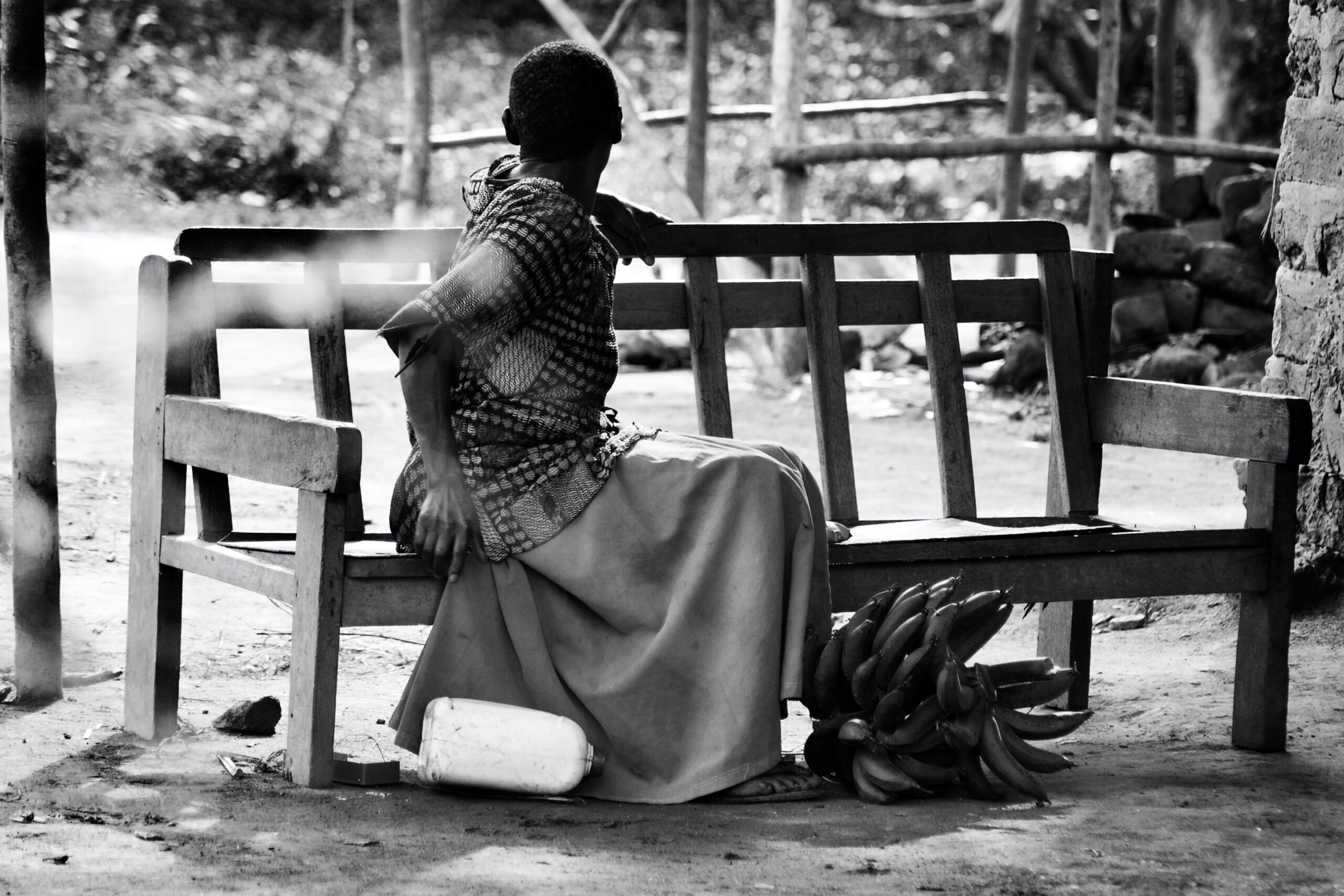 A person sitting contemplatively on a bench, embodying the Law of Visualisation in a serene outdoor setting.