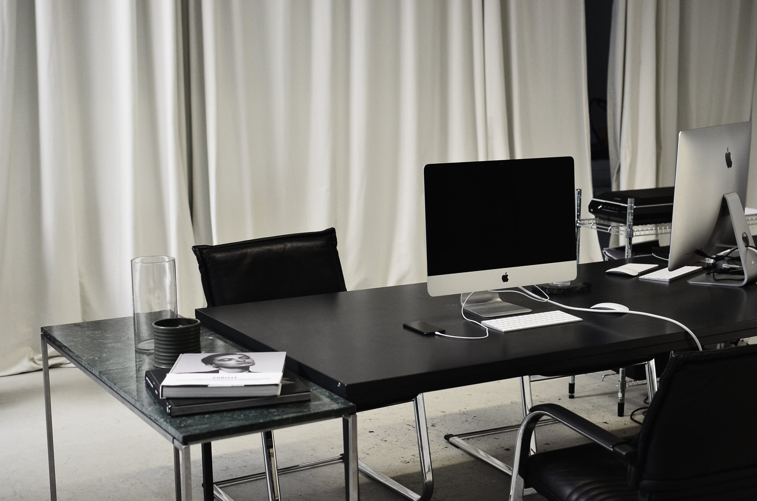 Modern minimalist workspace with two Apple iMacs and marketing books, embodying the sleek efficiency of social media success.