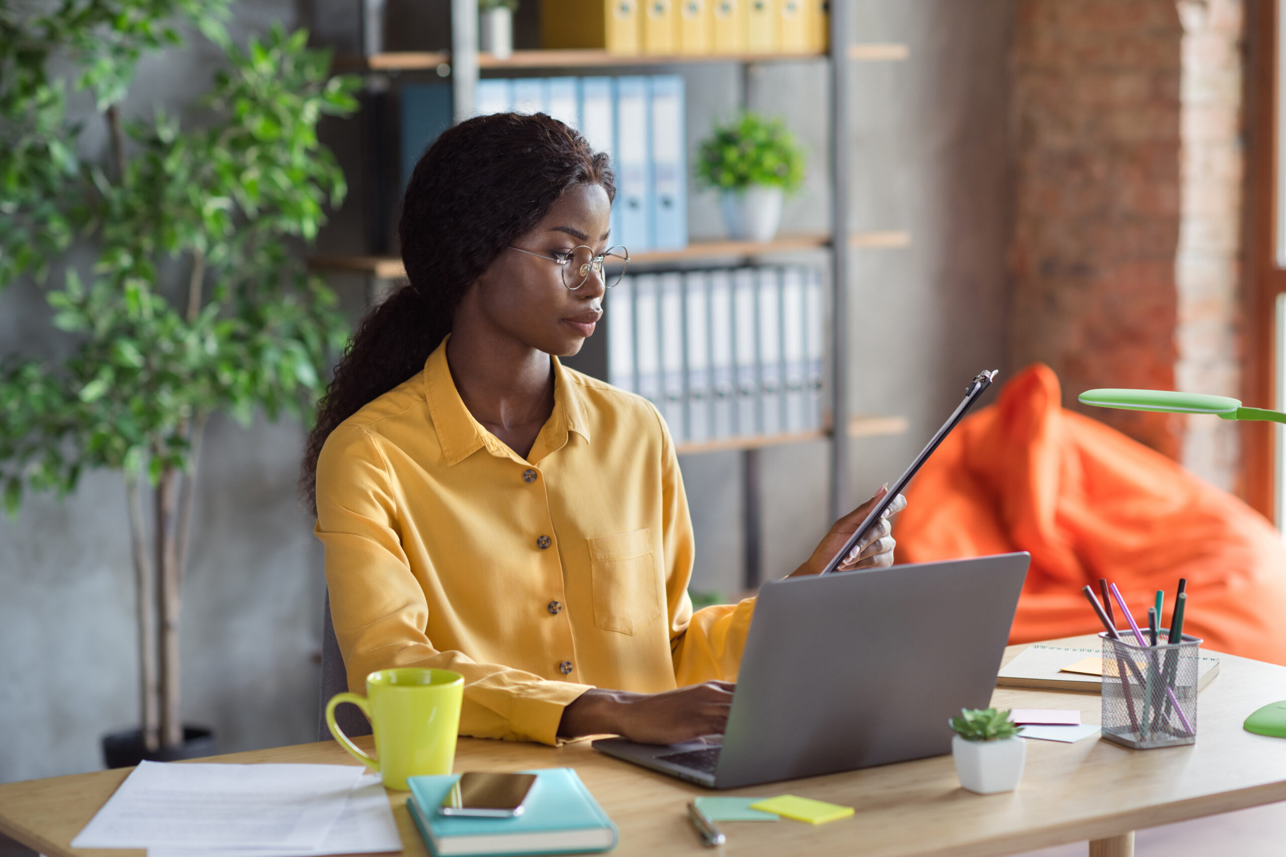 Focused entrepreneur engaged in planning empowering weekly goals on a laptop in a modern workspace.