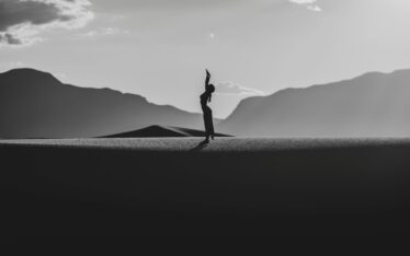 Visionary Resilience: Silhouette of a person standing confidently on a horizon, framed by mountains, embodying the spirit of visionary leadership and future aspirations.