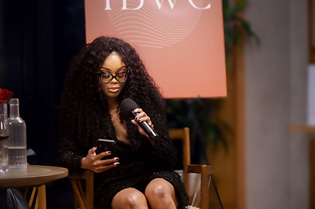 Spiritual Success Coach, Bess Obarotimi sitting in a chair holding a microphone
