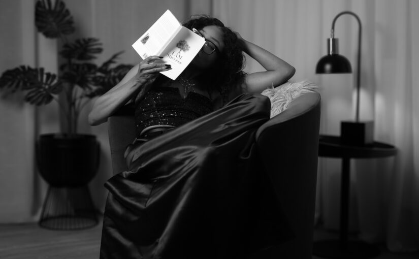 Black-and-white photo of Bess Obarotimi holding her book I AM Success while seated on a chair, illustrating how to read I AM Success with calm reflection.