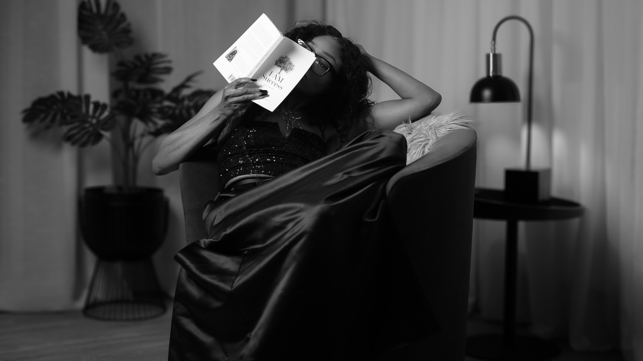 Black-and-white photo of Bess Obarotimi holding her book I AM Success while seated on a chair, illustrating how to read I AM Success with calm reflection.