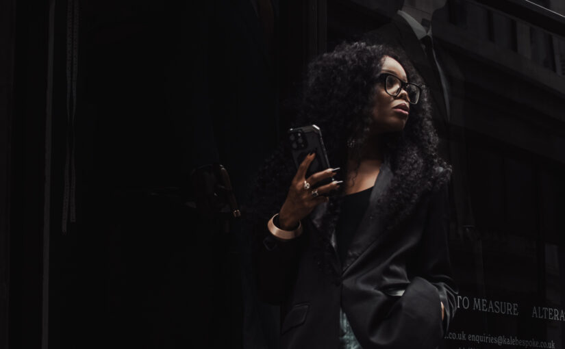 Professional woman in a dark urban setting using her phone, representing the AI productivity divide and modern workplace performance differences.