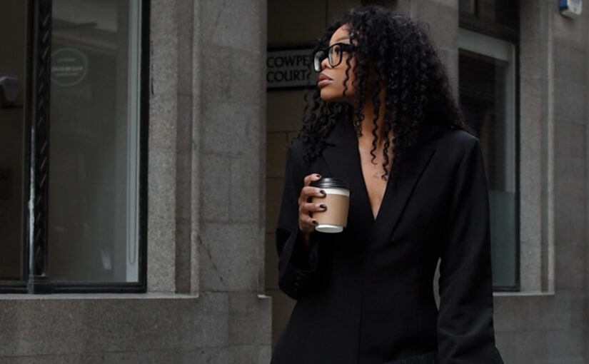 Professional woman holding coffee outside office building, representing leadership, decision making, and AI governance in practice